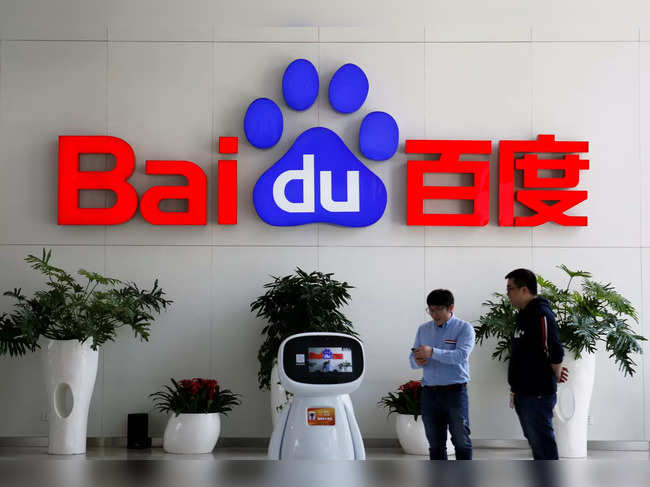 FILE PHOTO: Men interact with a Baidu AI robot near the company logo at its headquarters in Beijing