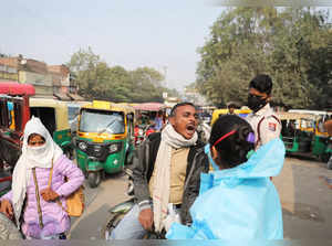 A healthcare worker collects a coronavirus disease (COVID-19) test swab sample from a man on a road in New Delhi