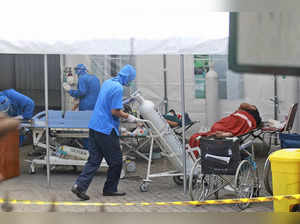 A medical worker wheels an oxygen tank