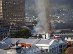 Cape Town: Firemen spray water on flames erupting from a building at South Afric...