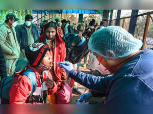 New Delhi: A health worker takes swab sample of a child passenger for COVID-19 t...