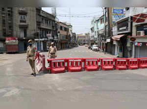 Jammu: Police officers stand vigil during COVID-induced curfew at a market in Ja...