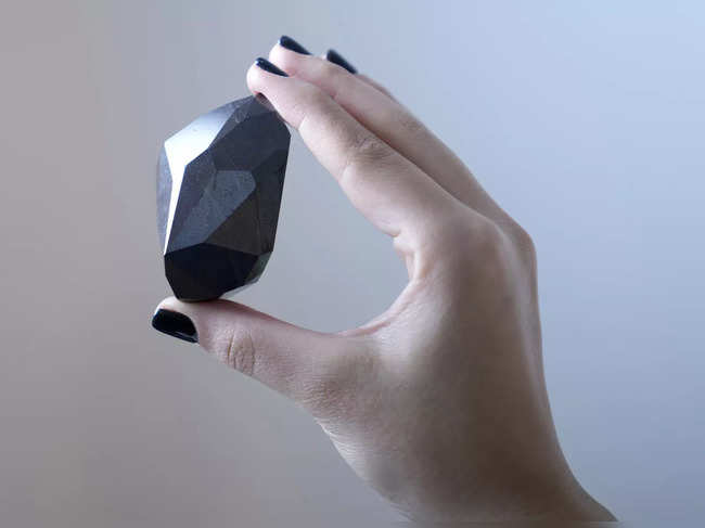 An employee of Sotheby's Dubai presents a 555.55 Carat Black Diamond 'The Enigma'.