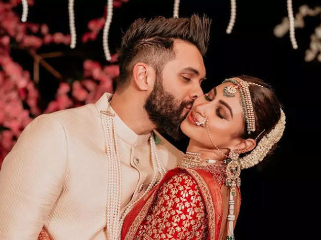 Mouni Roy dazzled in a red-gold lehenga by designer Sabyasachi Mukherjee, and Suraj Nambiar opted for a classy beige Sherwani.​