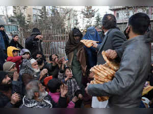 An Afghan woman receives a loaf of bread in front of a bakery among the crowd in Kabul