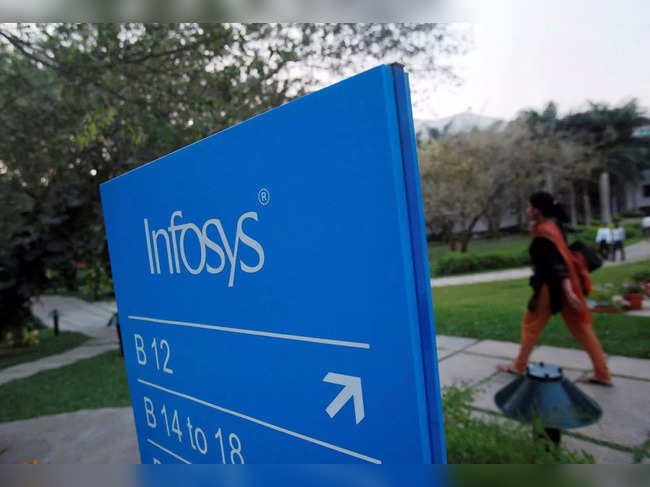 FILE PHOTO: An employee walks past a signage board in the Infosys campus at the Electronics City IT district in Bangalore