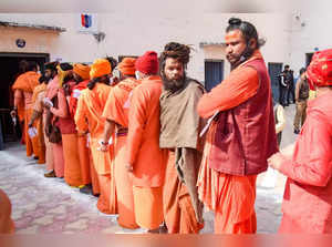Haridwar: Sadhus of 'Juna Akhara' stand in a queue to cast their votes, during t...