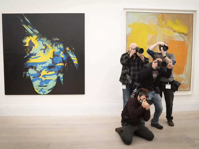 ​London photographers take photos near to the artwork, Andy Warhol, Self-Portrait, 1986, during a photo call for artworks from the Macklowe Collection at Sotheby's, prior to the collection being offered at auction in New York​.