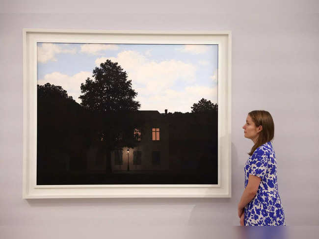 FILE PHOTO: A Sotheby's employee poses with the artwork 'L'empire des lumieres, 1961' by Rene Magritte, on display ahead of auction at Sotheby's in London
