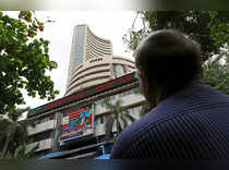 A man looks at a screen across a road displaying the Sensex on the facade of the Bombay Stock Exchange (BSE) building in Mumbai
