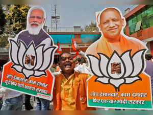 A supporter of BJP displays cut-outs of PM Modi and Chief Minister of Uttar Pradesh Yogi Adityanath  in Lucknow