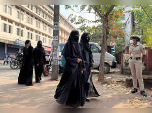 FILE PHOTO: Hijab wearing schoolgirls arrive to attend their classes as a policewoman stands guard at a government girls school in Udupi town