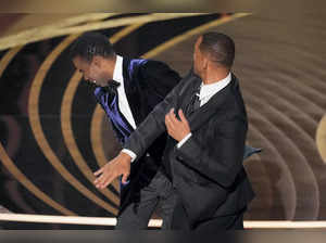 Will Smith, right, slaps presenter Chris Rock on stage while present...