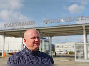 Valery Uglov, an auto mechanic at the Volkswagen Group Rus plant, stands in front of the entrance to the plant in Kaluga