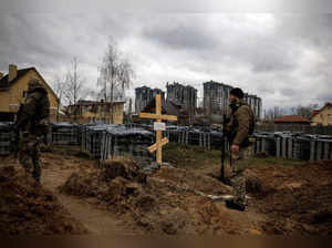 Ukrainian soldiers stand next to the grave of a civilian in Bucha