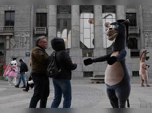 A street animator wearing a horse costume comes up to people