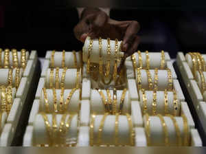 A salesman arranges gold bangles inside a jewellery showroom.