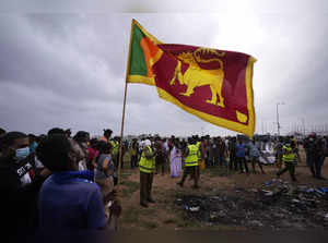 Colombo: A Sri Lankan man holds a national flag as police officers conduct inves...