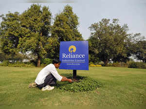 A gardener works next to a board of Reliance Industries Ltd at Gandhinagar in Gujarat