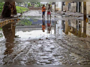 Bengaluru: Children walk on a waterlogged road after heavy rain in Bengaluru. (P...