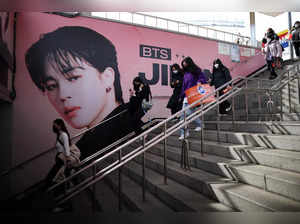 Fans of K-pop boy band BTS walk past an advertisement promoting their concert at Seoul Olympic stadium in Seoul