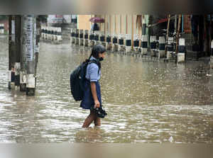 Guwahati, May 13 (ANI): A child crossing a waterlogged road of Anil Nagar after ...