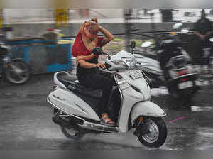 Surat: A  commuter rides a two-wheeler amid rainfall, that brings respite from t...