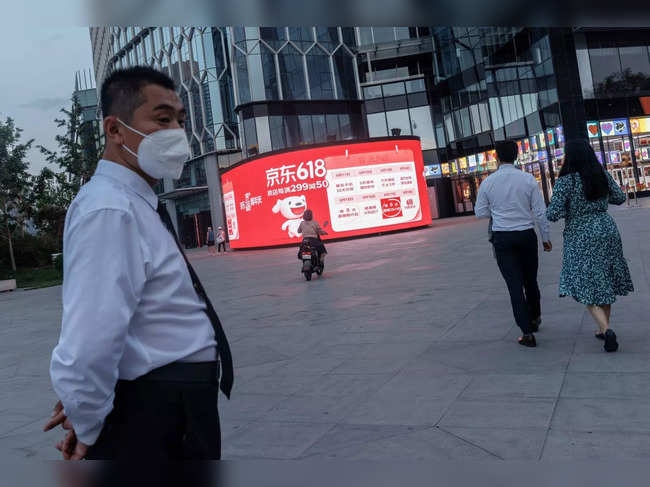 People walk near a JD.com advertisement for the "618" shopping festival in a shopping district in Beijing
