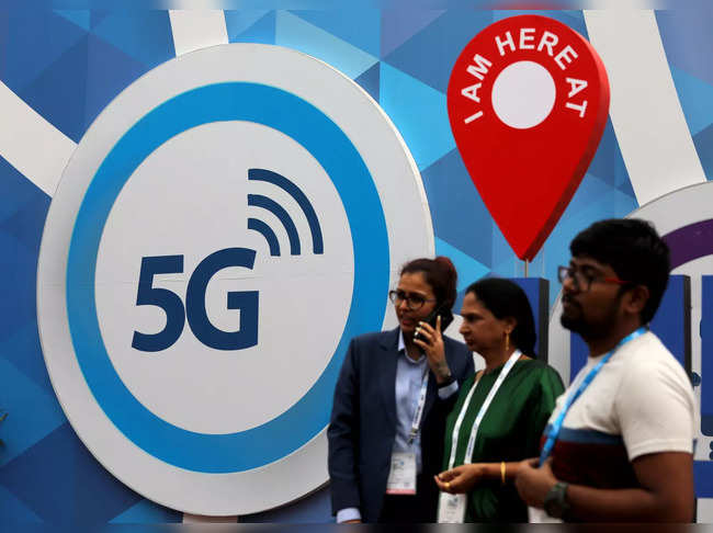 People stand in front of a board depicting 5G network at the India Mobile Congress 2018 in New Delhi