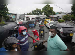People wait in a long queues to buy fuel for their vehicles at a filling station...