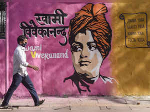 New Delhi: A man wearing a face mask walks past a wall mural of Swami Vivekanand...