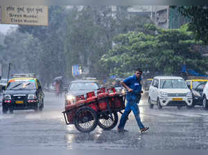 Mumbai: Commuters move on a road amid monsoon rains, in Mumbai. (PTI Photo)(...