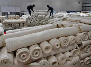 Workers stack cotton fabric rolls at a textile factory of Texport Industries in Hindupur