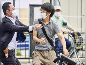 Tetsuya Yamagami, left, holding a weapon, is detained near the site of gunshots ...
