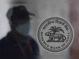 A man walks behind the Reserve Bank of India (RBI) logo inside its headquarters in Mumbai