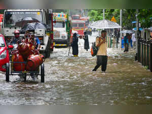 Mumbai: Commuters wade through a waterlogged road following Monsoon rains, in Mu...