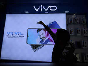 FILE PHOTO: A man cleans a screen displaying a phone model of Chinese smartphone maker Vivo inside a shop in Ahmedabad