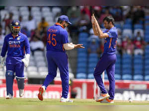 India's Ravi Bishnoi celebrates with captain Rohit Sharma after he bowled West I...