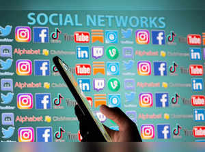 FILE PHOTO: Woman with smartphone is seen in front of displayed social media logos in this illustration taken