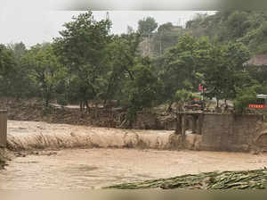 A vehicle is seen near a part of a bridge that was washed away by flood waters a...