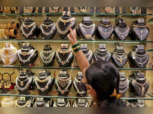 A saleswoman shows gold necklaces to a customer at a jewellery showroom during Dhanteras, in Mumbai