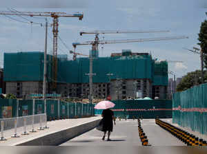 FILE PHOTO: A woman walks near a construction site of apartment buildings in Beijing