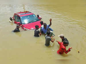 People pull a car through a water-logged road following torrential rains in Bengaluru
