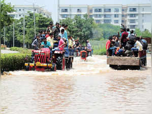 Bengaluru, Sept 06 (ANI): Tractors carrying people wade through a waterlogged ro...