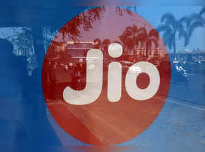 FILE PHOTO: Commuters are reflected on an advertisement of Reliance Industries' Jio telecoms unit, at a bus stop in Mumbai