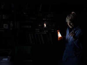 Olga Kobzar stands in her living room as she holds a battery light in her apartment in Saltivka neighbourhood of Kharkiv