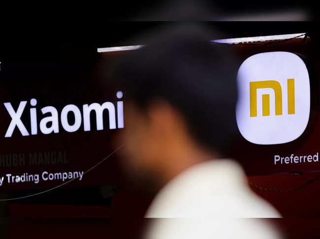 FILE PHOTO: A man walks past a logo of Xiaomi, a Chinese manufacturer of consumer electronics, outside a shop in Mumbai