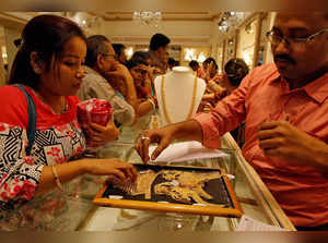 FILE PHOTO: A salesman shows gold necklaces to a customer at a jewellery showroom during Dhanteras, a Hindu festival associated with Lakshmi, the goddess of wealth, in Kolkata