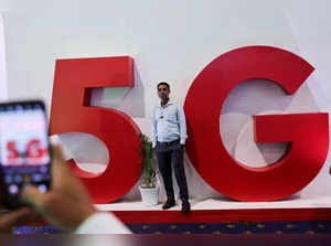 FILE PHOTO: A man takes a picture of a friend in front of a sign showing installation of the 5G network