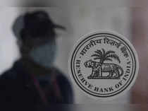 FILE PHOTO: A man walks behind the Reserve Bank of India (RBI) logo inside its headquarters in Mumbai